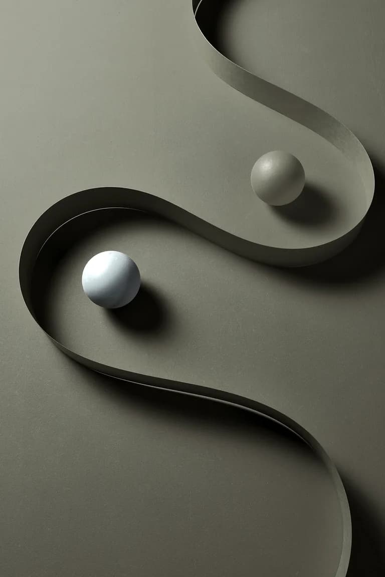 Balanced sculptural spheres resting on curved forms